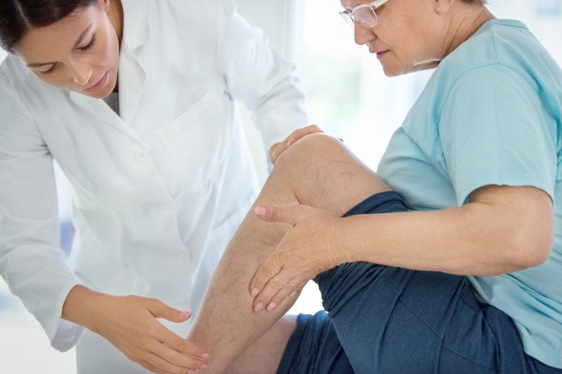 Doctor examining elderly patient’s leg for vascular conditions in Phoenix, AZ, & surrounding areas